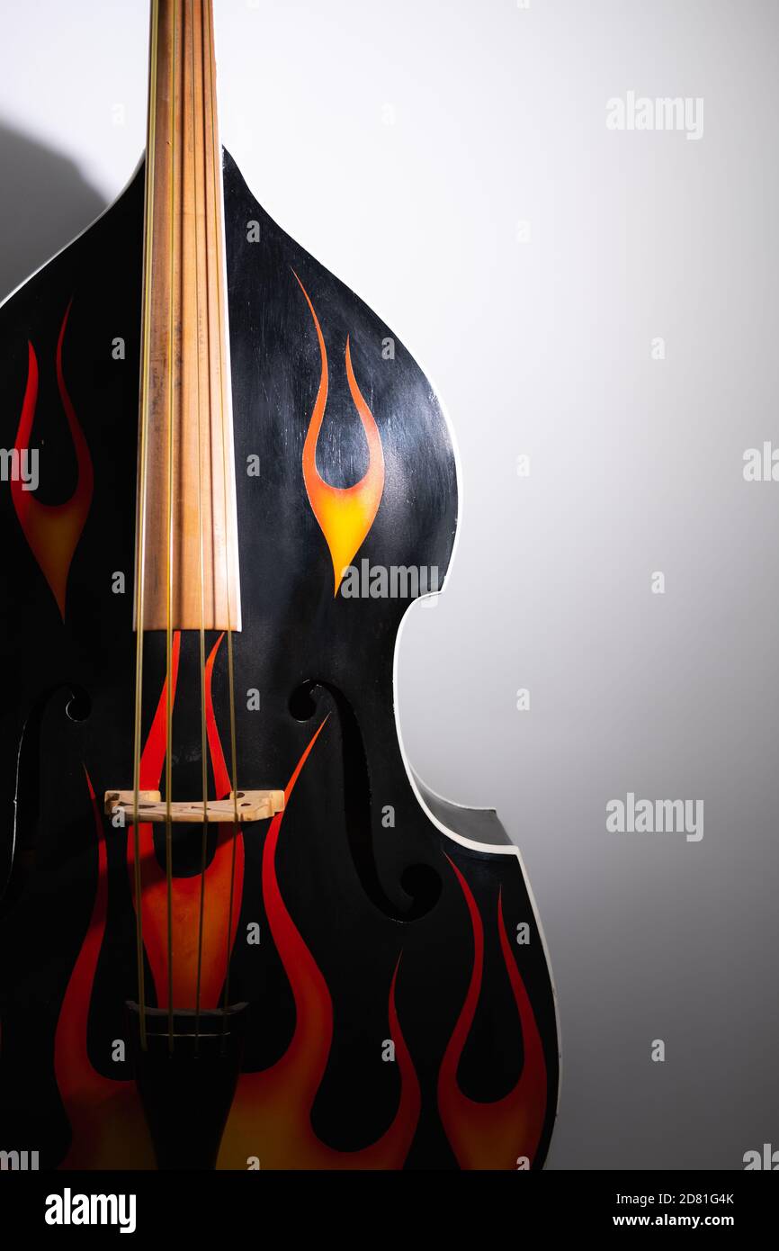 Akustischer Kontrabass mit Flammenabziehbildern. Rock'n'Roll, Rockabilly Musikinstrument im Studio Hintergrund Stockfoto