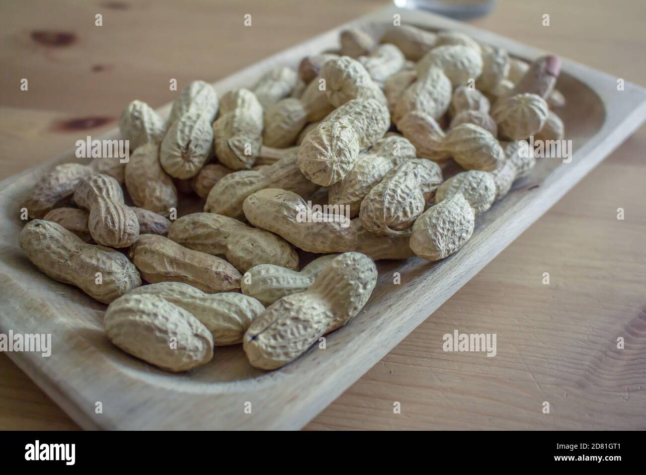 Einige ganze amerikanische Erdnüsse mit Schale in einem rechteckigen Holz Fach Stockfoto