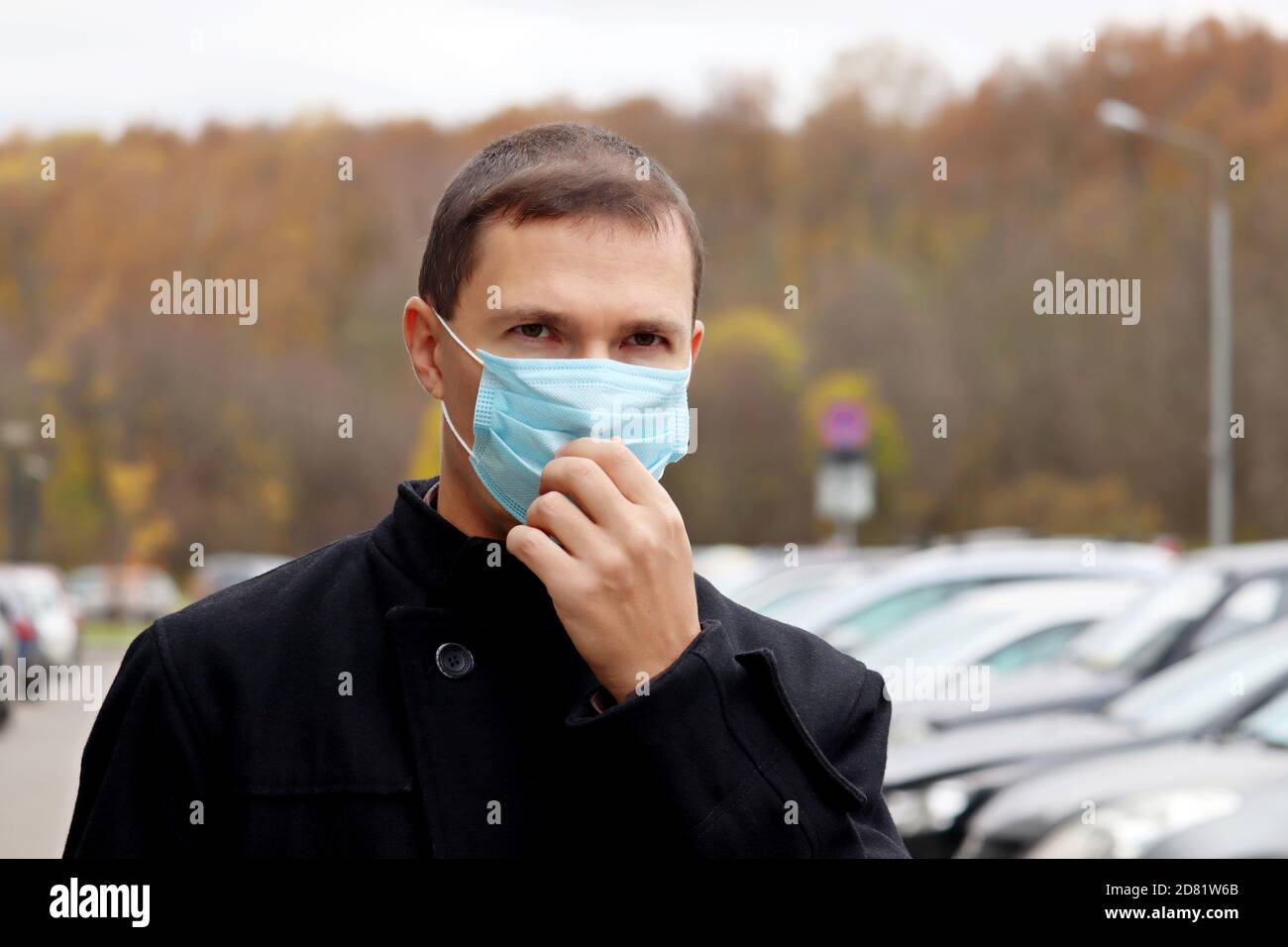Coronavirus Schutz im Herbst, Mann in Einweg-Gesichtsmaske auf einer Stadtstraße Stockfoto