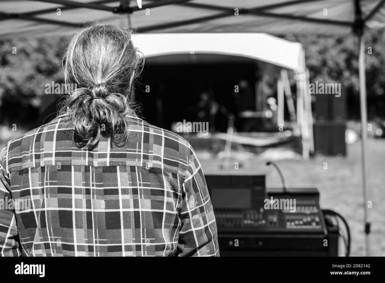 Schwarz-weiße Rückansicht des älteren Mannes mit lang Haare stehen hinter elektronischen Sound Equalizer beim Blick auf die Bühne In kulturellen Fiesta Stockfoto