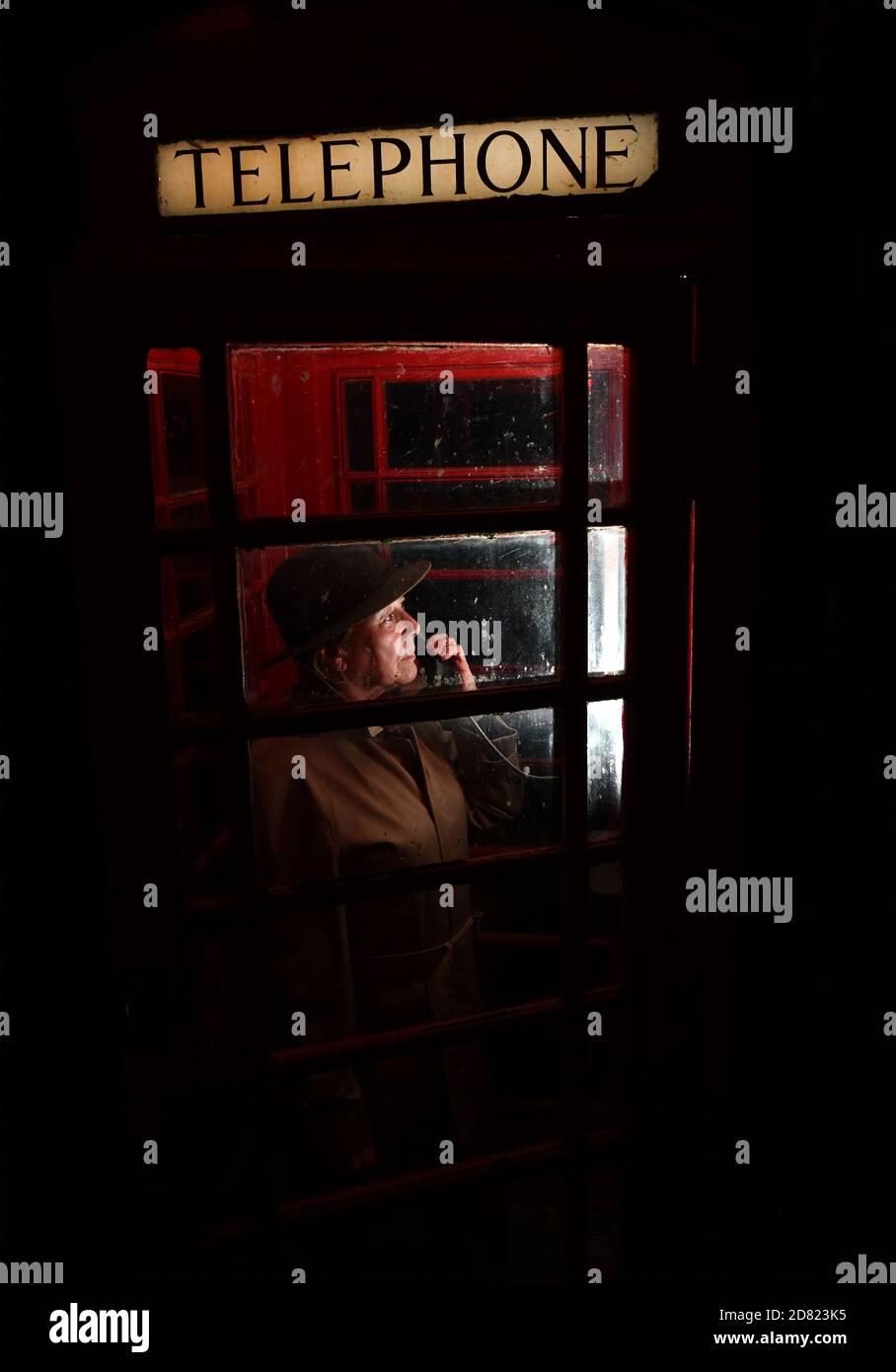 Person, die eine öffentliche Telefonbox bei Night Britain, UK nutzt Stockfoto