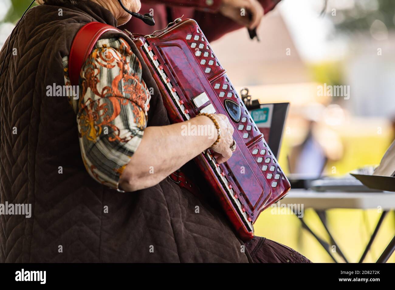 Selektiver Fokus der reifen Person trägt und spielt Akkordeon-Musical Instrument mit Bezug auf Noten im Buch in Kultur fiesta Stockfoto