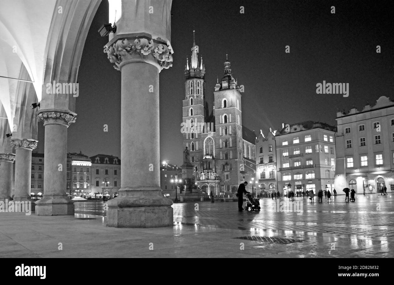 Aus der Tuchhalle, einer regnerischen Nacht auf dem Marktplatz aus dem 13. Jahrhundert in Krakau, Polen, kann man die gotischen Türme der Marienbasilika erhellen. Stockfoto