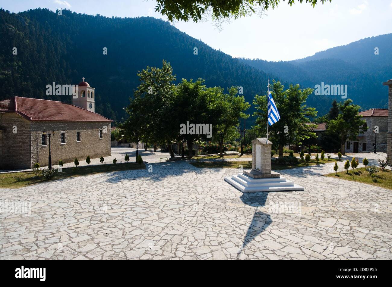 Platz mit Kirche und griechischer Flagge im Bergdorf Koryshades, Griechenland Stockfoto