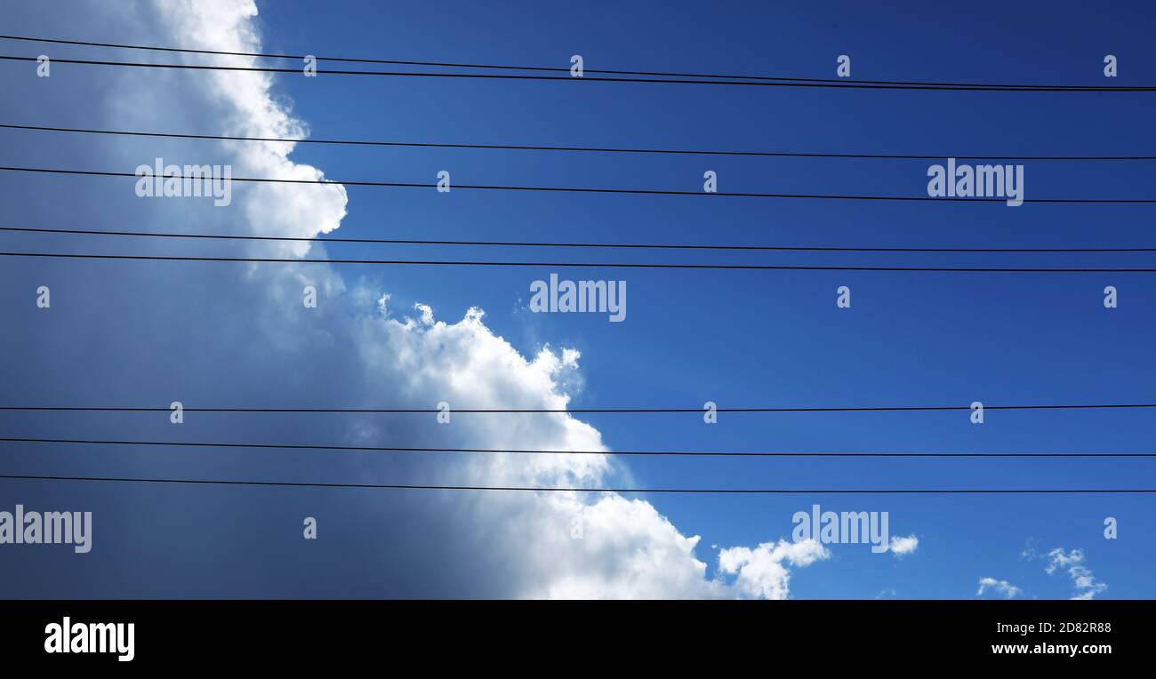 Interessante alternative kreative Ansicht Blick durch Stromleitungen zu weißen flauschigen Wolken Gebäude bis zu einem tropischen Gewitter. Intensiv tief BL Stockfoto