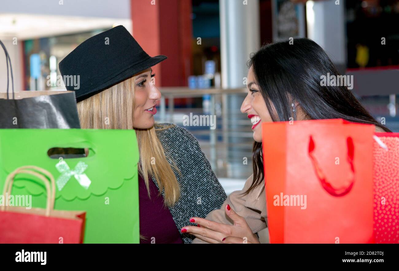 Zwei junge blonde und brünette Freunde sitzen in einem Kaffee Einkaufen nach einem Verkaufstag mit vielen bunten Taschen mit Ihre Einkäufe Stockfoto