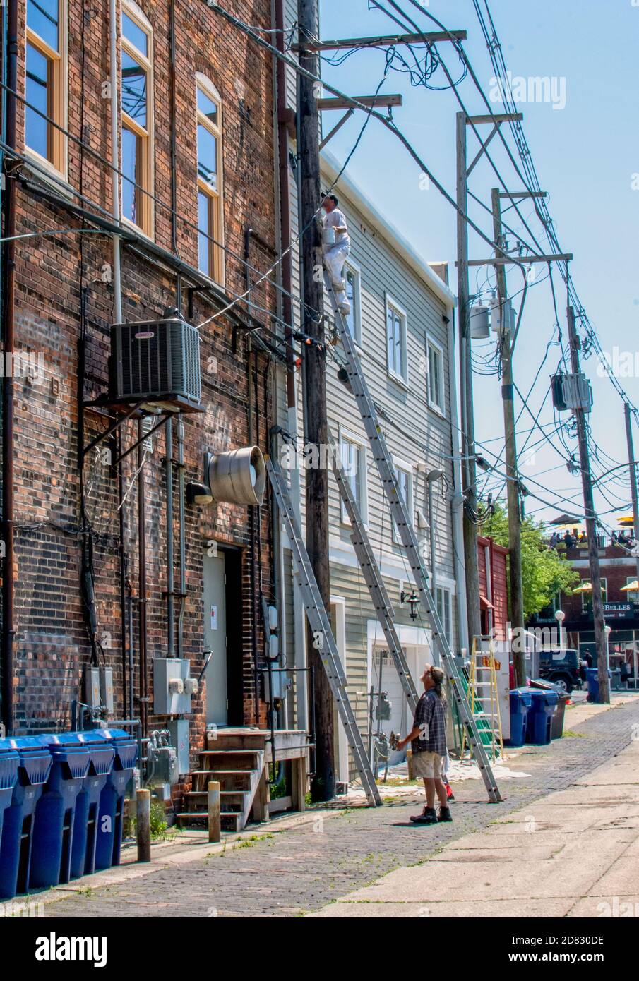 St Joseph MI USA June 12 2020; Arbeiter auf einer hohen Leiter repariert ein Gebäude in einer Innenstadt, während ein Mitarbeiter für Sicherheit steht Stockfoto