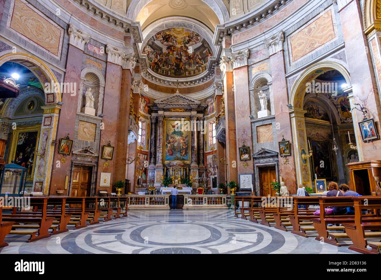 Menschen in der Kirche, im Inneren von San Giacomo in der Augusta Kirche, Deckenfresken, Gewölbe und Altaraufsatz, Rom, Italien. Stockfoto