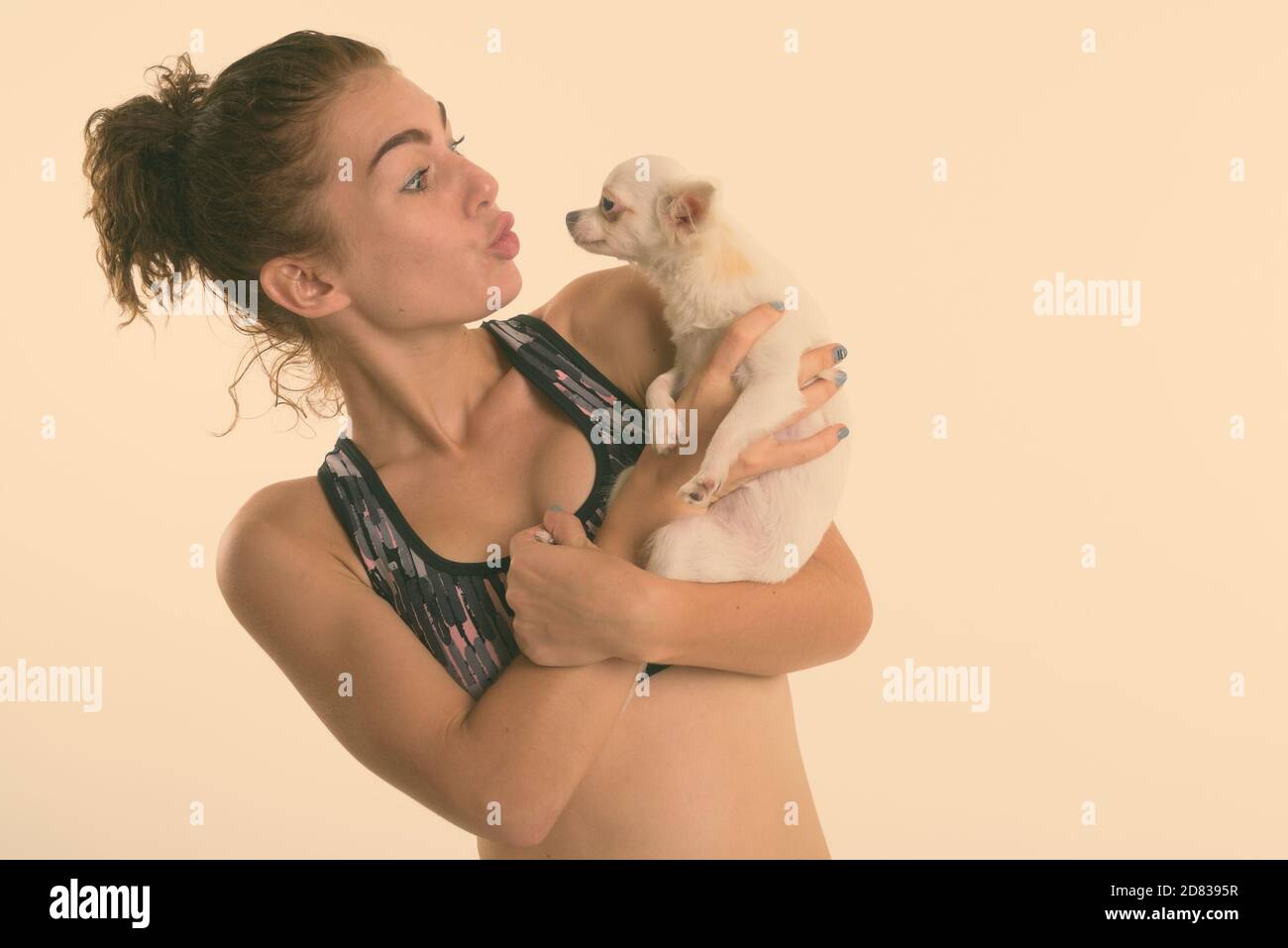 Studio schoss der schönen Teenager halten und küssen niedlichen Hund für Sport und Bewegung gegen den weißen Hintergrund bereit Stockfoto