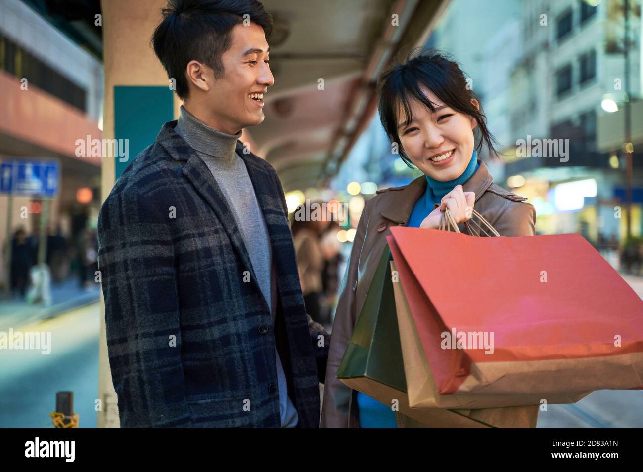 Glücklich und liebevolle junge asiatische Paar im Busbahnhof stehen Mit Einkaufstaschen in der Hand Stockfoto