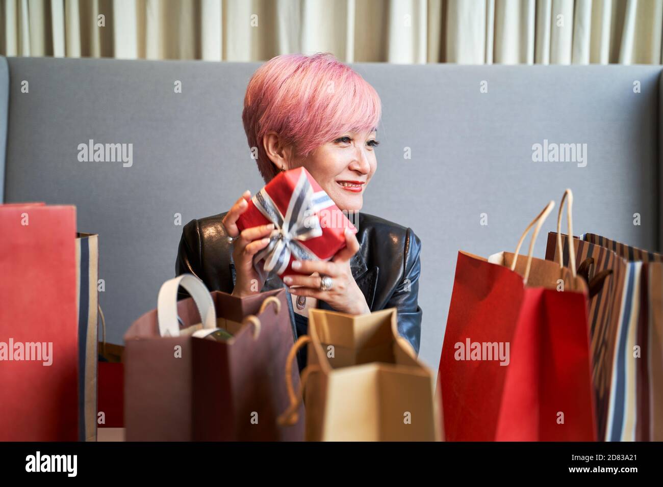 Junge asiatische Frau sitzt in Couch entspannen nach weihnachtsgeschenke Einkaufen Stockfoto