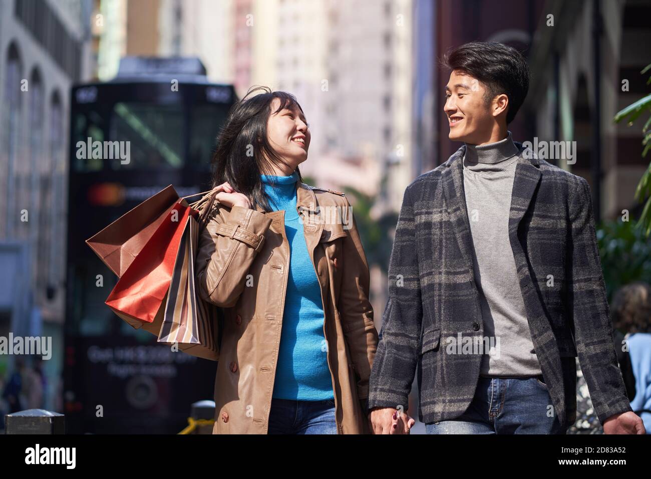 Glücklich und liebevolle junge asiatische Paar auf der Straße mit Einkaufstaschen in der Hand Stockfoto