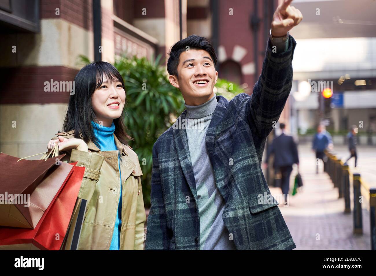 Glückliches und liebevolles junges asiatisches Paar, das in der modernen Stadt einkauft Stockfoto