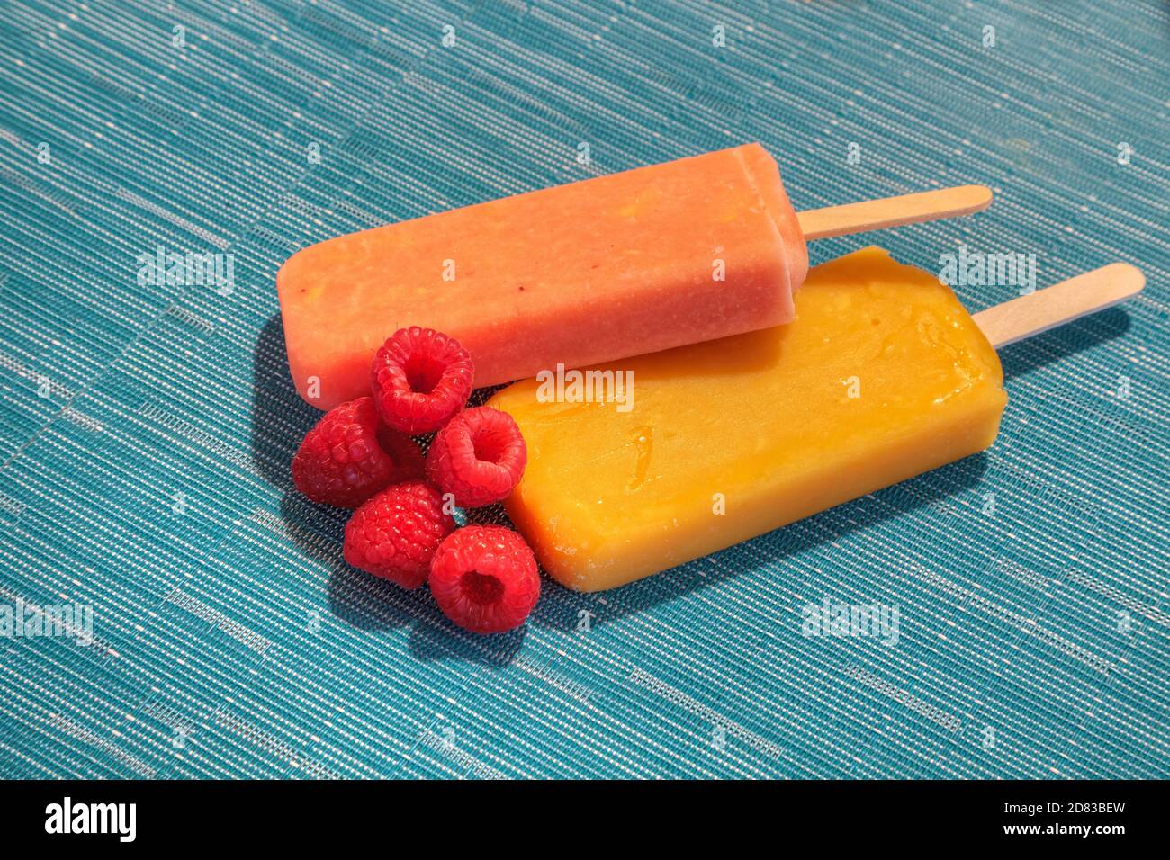 Fruchtpopsicles auf einem aquabluen Hintergrund im Sommer einschließlich Wassermelone Popsicle, tropische Frucht Popsicle, Mango Popsicle, und Limettenpopsicle mit Fr. Stockfoto