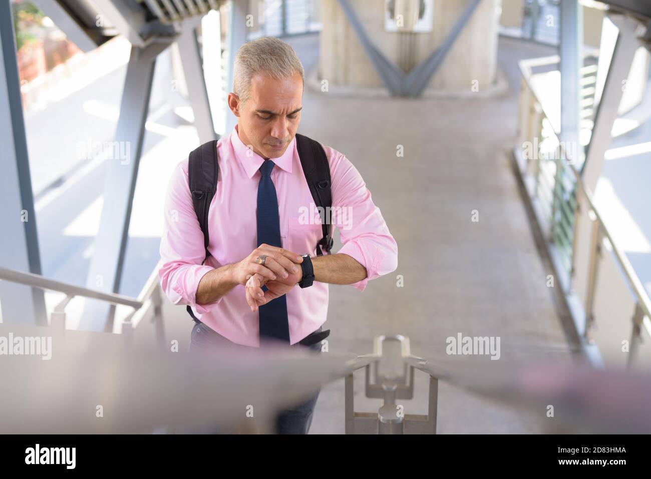 Schöner persischer Geschäftsmann, der die Zeit an der Fußgängerbrücke überprüft Stockfoto