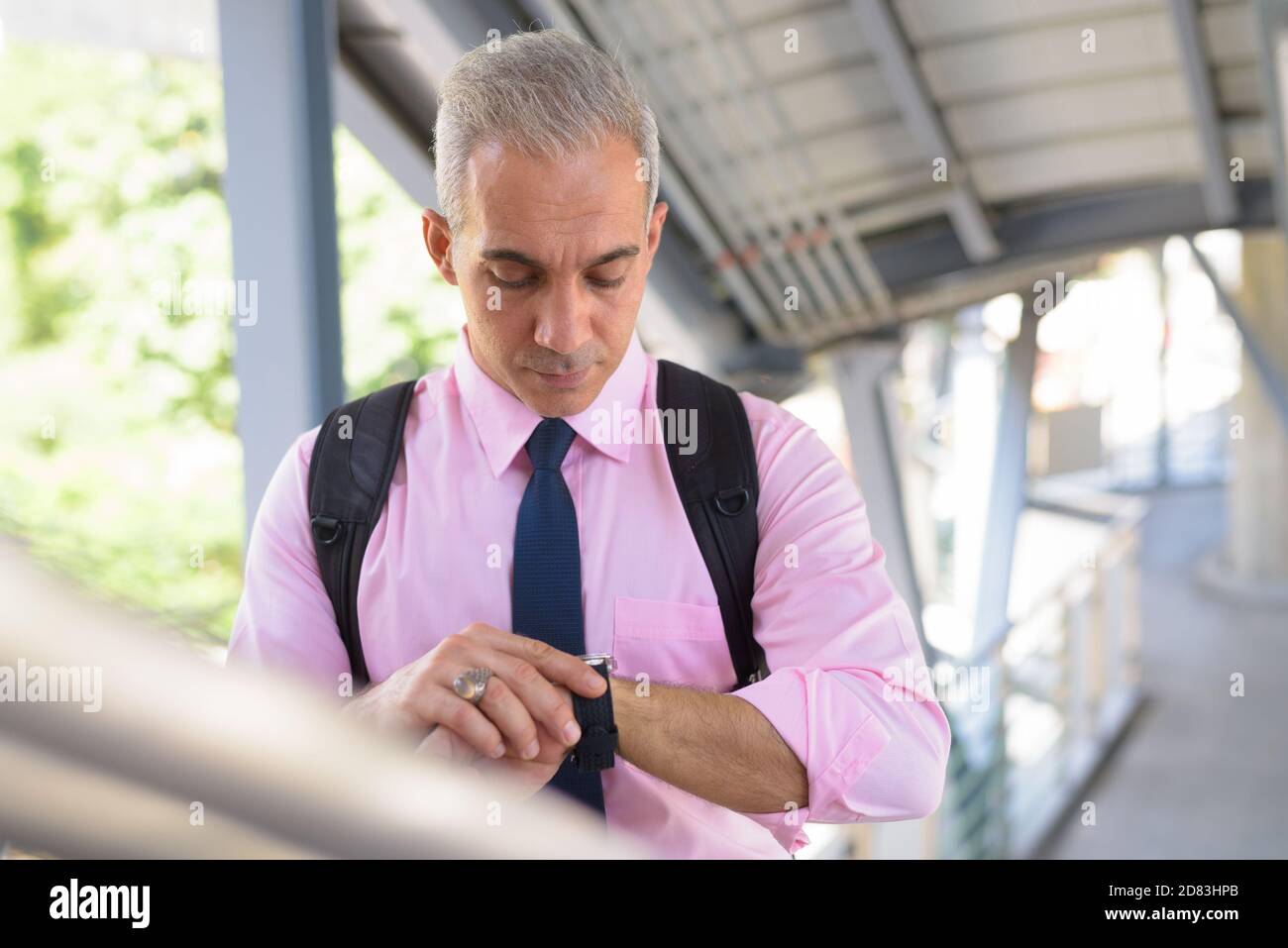 Schöner persischer Geschäftsmann mit Rucksack in der Stadt überprüfen die Zeit Stockfoto