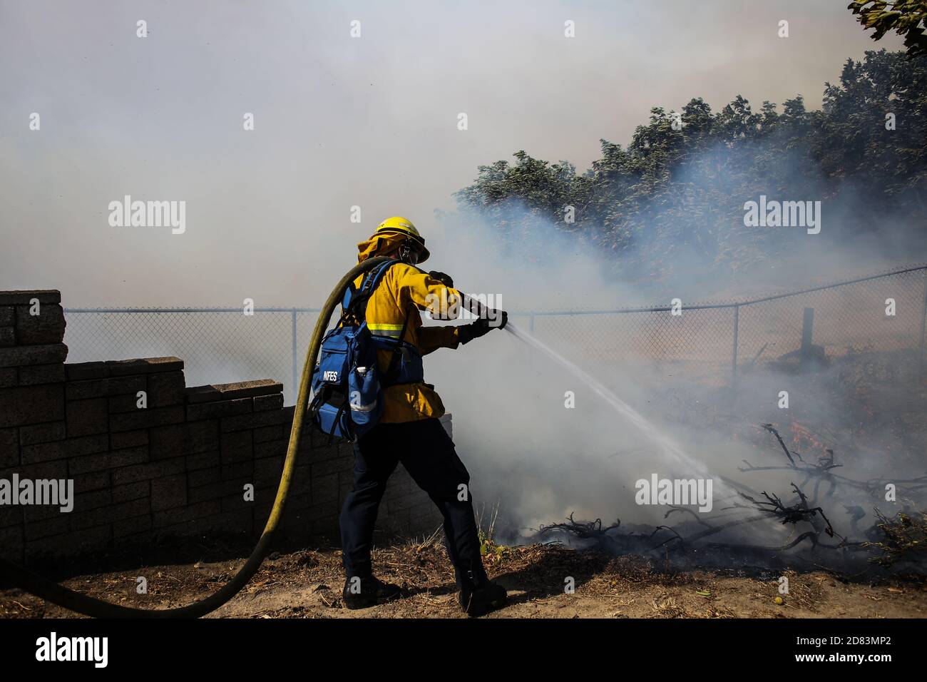 Irvine, Usa. Oktober 2020. Ein Feuerwehrmann löscht ein Feuer an der Northwood High School in Irvine.am Montag, den 26. Oktober, um 6:47 Uhr begann das Silverado-Feuer als Brushfeuer im Silverado Canyon, Kalifornien, und als Santa Ana Winde wehten, traf das Feuer die Stadt Irvine in Orange County, Kalifornien. Der Brand setzt sich fort, da die Löschkräfte derzeit daran arbeiten, den Brand einzudämmen. Kredit: SOPA Images Limited/Alamy Live Nachrichten Stockfoto