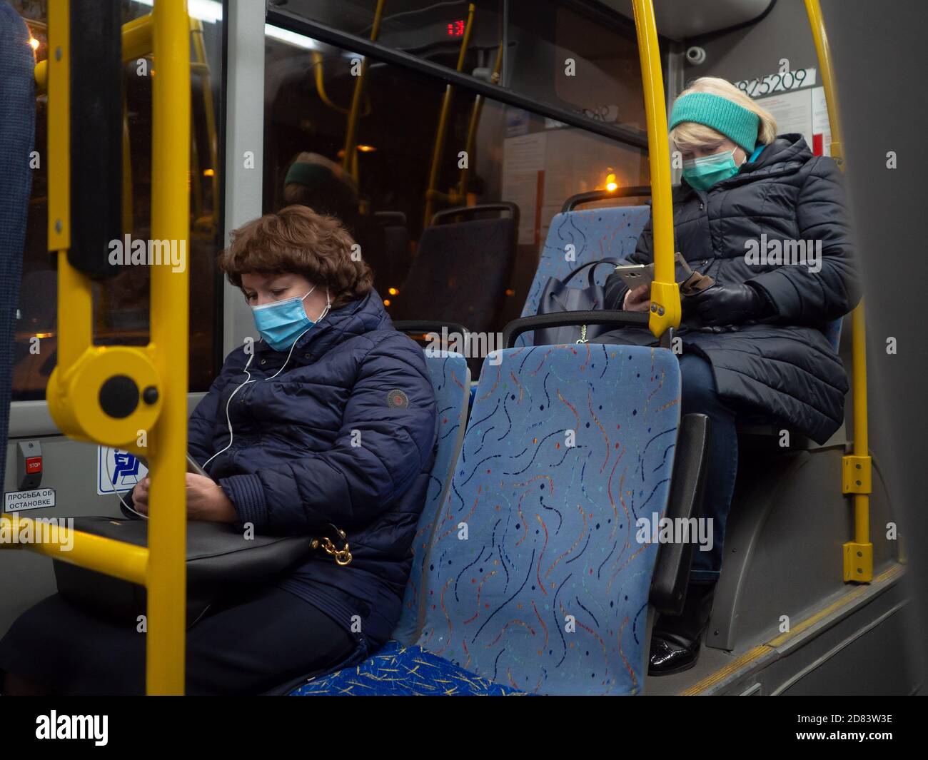 Moskau. Russland. 26. Oktober 2020. Zwei Frauen in einem Stadtbus lesen Nachrichten auf einem Smartphone-Bildschirm. Auf den Gesichtern der Passagiere sind Schutzmasken. Der Stockfoto
