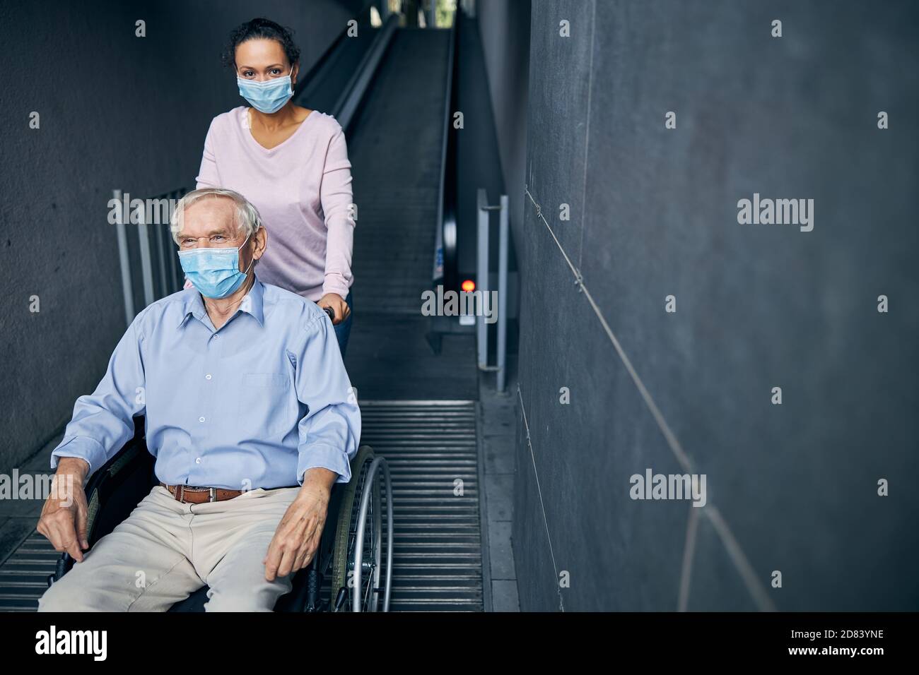 Junge Frau hilft für alten Mann zu gehen die Rolltreppe Stockfoto