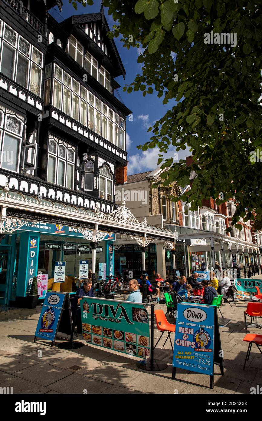 In Großbritannien, England, Merseyside, Southport, Lord Street saßen die Kunden in Sonnenschein vor dem Diva Café im viktorianischen Tudorbethan-Gebäude Stockfoto