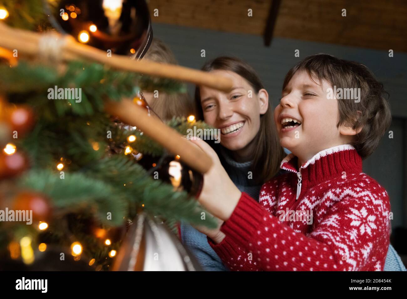 Glückliche Mutter und kleiner Sohn schmücken Weihnachtsbaum zu Hause Stockfoto
