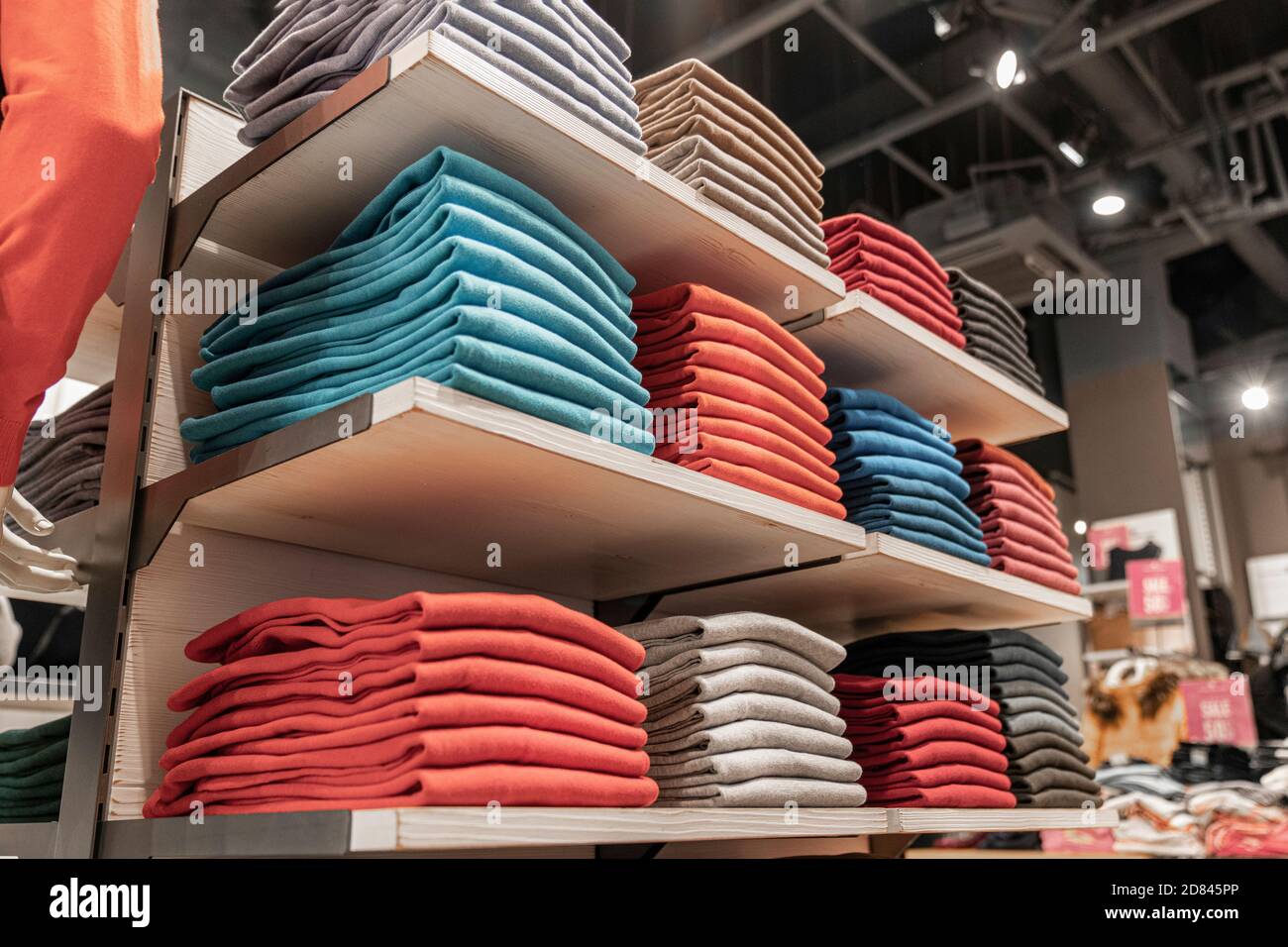 Gestapelte farbige Stapel von Kleidung in einem Boutique-Shop auf der Theke. Einkaufen vor Ort Stockfoto