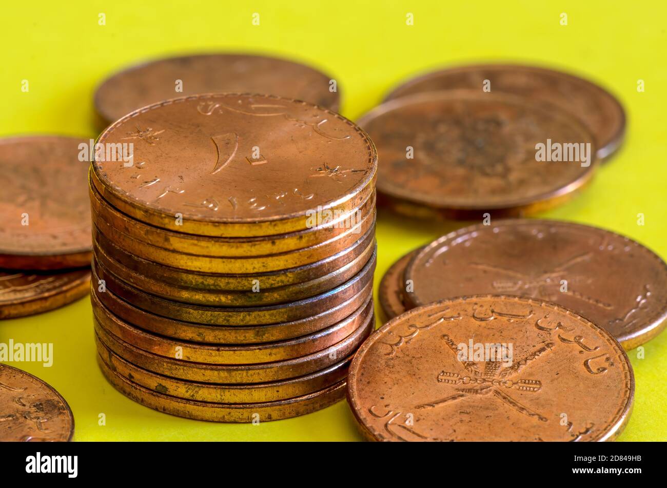 Der Stapel der omanischen 10 baiza Bronzemünzen auf dem gelben Hintergrund Stockfoto
