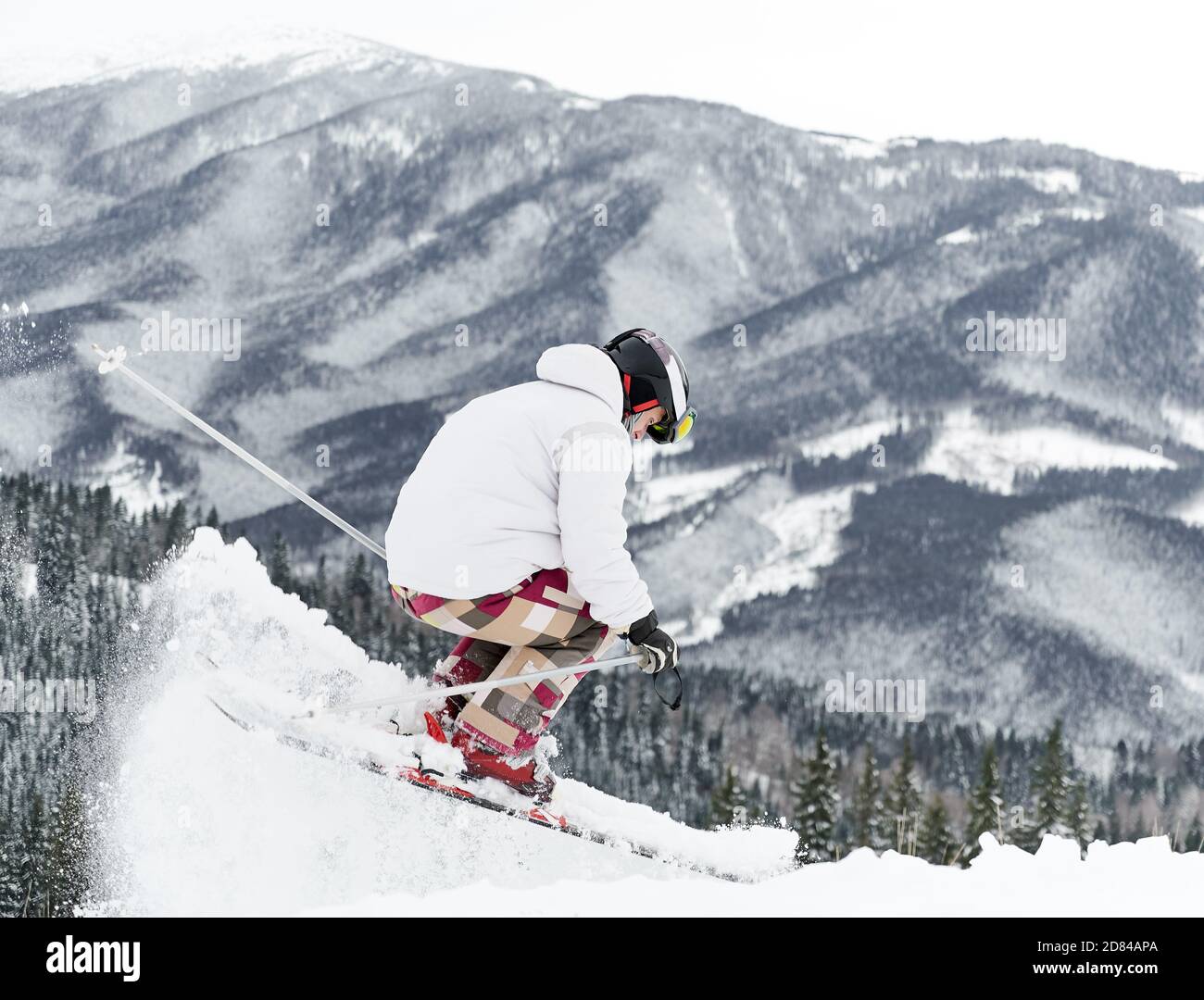 Winter Arten von Sport-Konzept. Rückansicht des Skifahrers, der Skianzug und Skiausrüstung trägt und Sprungtrick in der Wintersaison macht. Unterhaltung im Skigebiet in den Bergen, Kopierraum Stockfoto