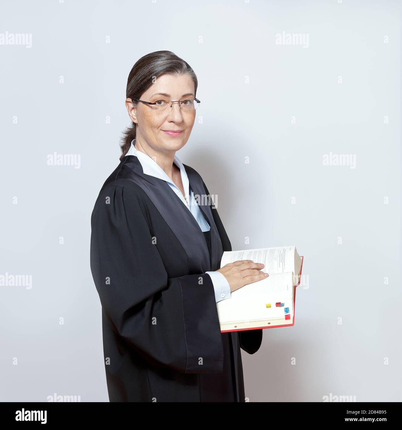 Weibliche Anwalt Konzept: Porträt einer Frau mittleren Alters in einem schwarzen Kleid mit einem gesetzgebenden Textbuch. Stockfoto