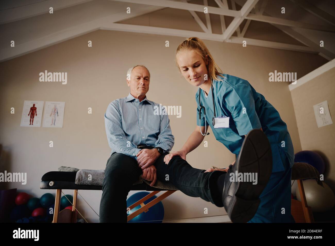 Älterer Rentner, der mit Hilfe von körperliche Übungen macht Professioneller Trainer Stockfoto