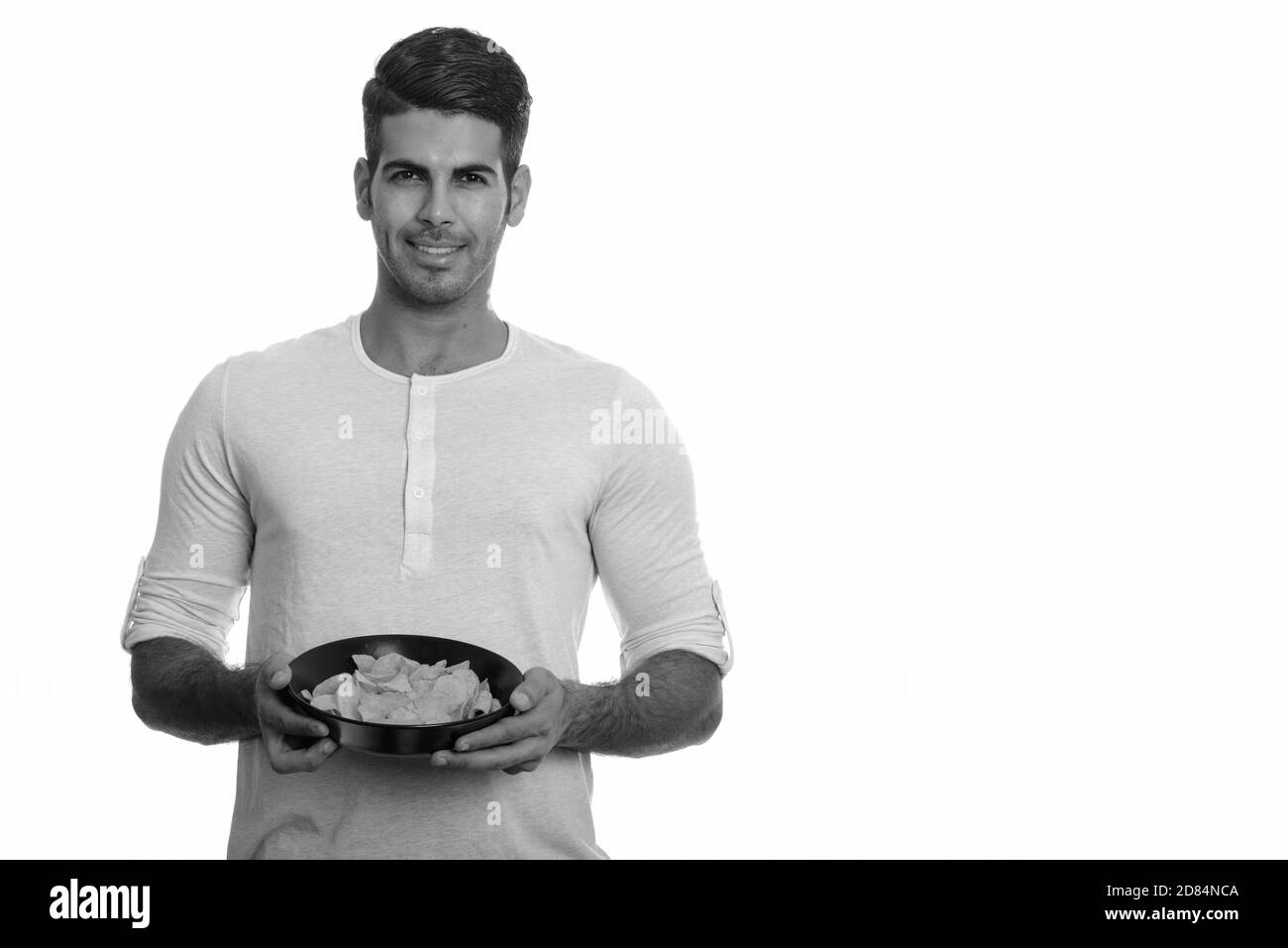 Junge glücklich Persischen Mann und lächelnd Schüssel Chips Stockfoto