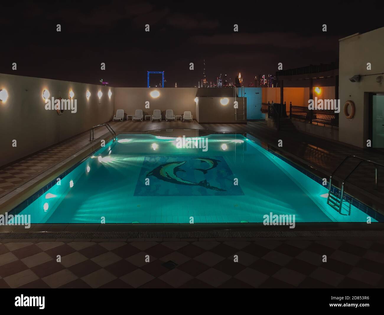 Nachtszene mit einem Pool auf dem Dach, beleuchtet und die wunderschöne Skyline von Dubai im Hintergrund. Stockfoto