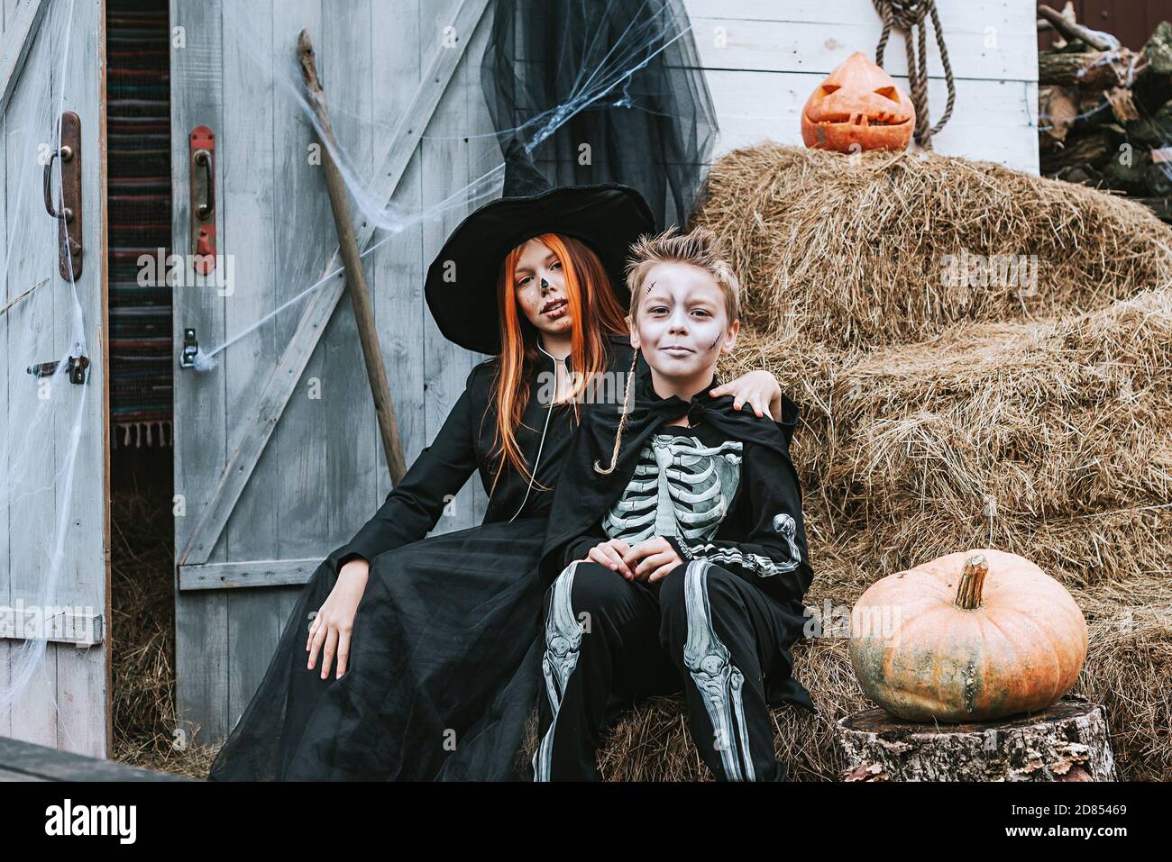 Kinder ein Junge in einem Skelett Kostüm und ein Mädchen In einem Hexenkostüm mit Spaß auf einer Halloween-Party Auf der dekorierten Veranda Stockfoto