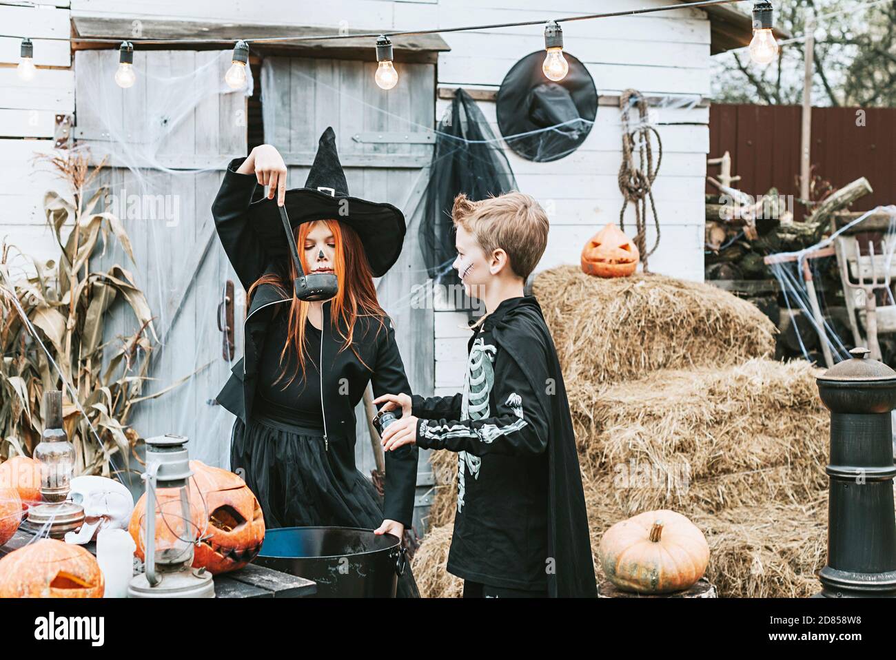 Kinder ein Junge in einem Skelett Kostüm und ein Mädchen In einem Hexenkostüm mit Spaß auf einer Halloween-Party Auf der dekorierten Veranda Stockfoto