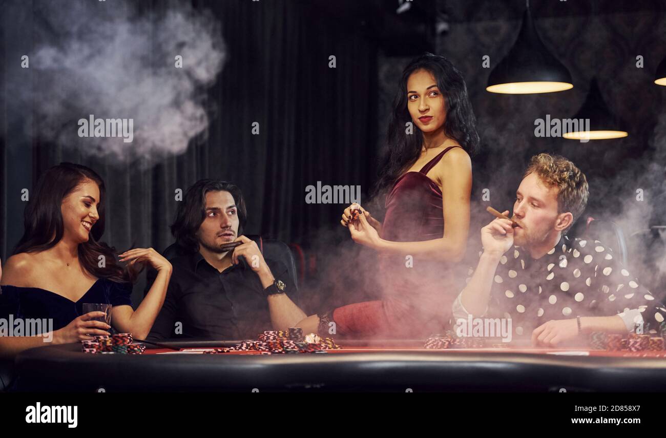 Gruppe von eleganten jungen Menschen, die Poker im Casino spielen Gemeinsam Stockfoto
