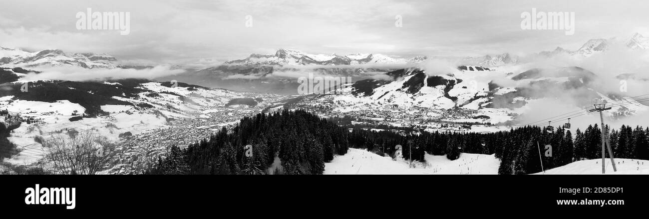 Eine Panorama-Schwarz-Weiß-Aufnahme der schneebedeckten französischen Alpen und der umliegenden Grenzen. Mit Skifahrern und Snowboardern. Stockfoto