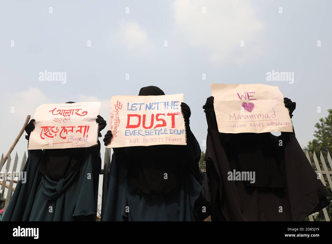Drei Frauen zeigen Plakate aus Protest gegen den französischen Präsidenten Emmanuel Macron in Dhaka. Muslimische Frauen protestieren in einem Aufruf zum Boykott französischer Produkte und verurteilen den französischen Präsidenten Emmanuel Macron für seine Bemerkungen ‘nicht aufgeben Karikaturen des Propheten Mohammed’. Stockfoto