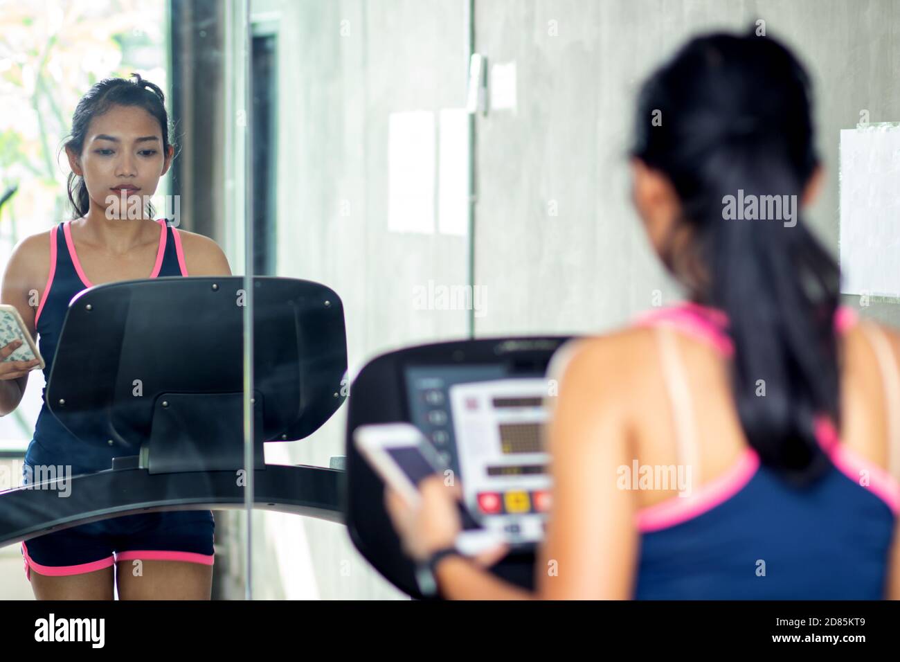 Junge Frau üben in der Turnhalle mit Spiegeln. Mädchen, die auf Laufband bei Fitness Club. Stockfoto