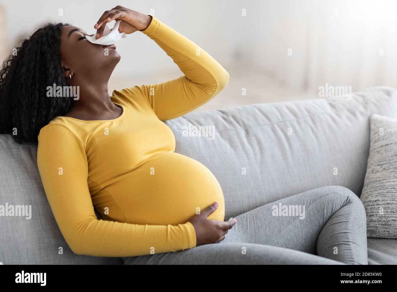 Schwarze schwangere Frau mit Nasenbluten oder Blutungen aus ihrer Nase Stockfoto