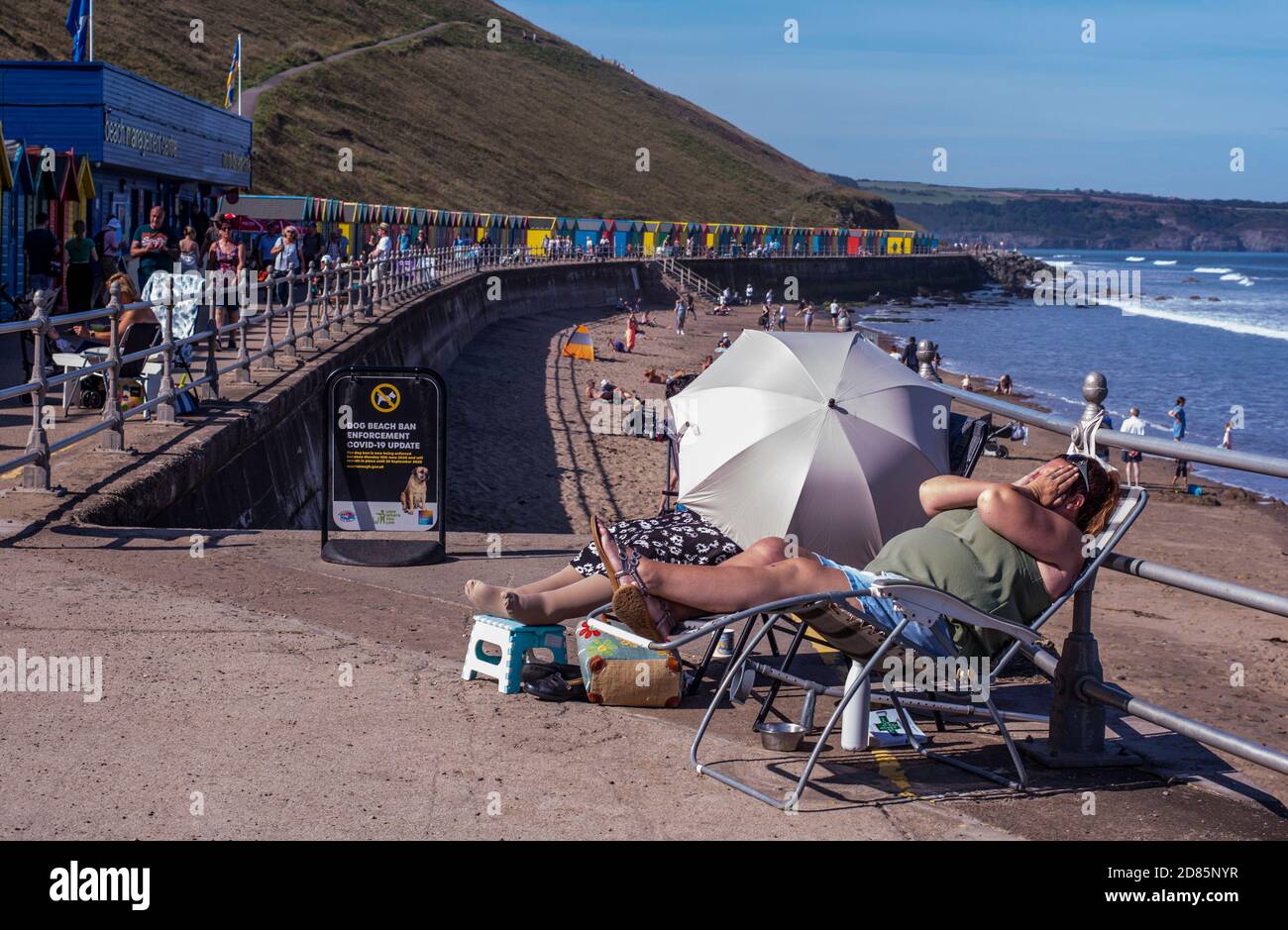 Frau, die sich auf der Sonnenliege am Strand, Whitby, England, Großbritannien, entspannt Stockfoto
