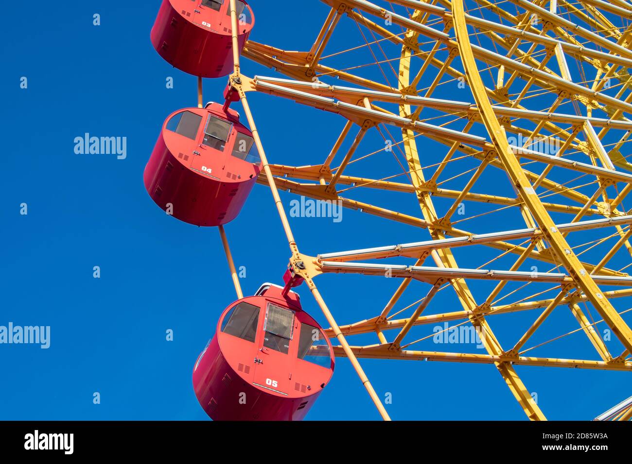 Riesenrad mit roten Kabinen rotieren gegen blauen Himmel. Stockfoto