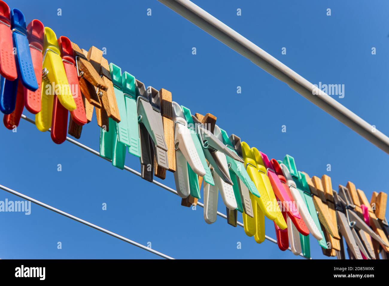 Eine farbige Kleidung hängt an einem Trockengestell Draht. Eine Gruppe von Wäscheklammern in der Linie gegen den blauen Himmel. Stockfoto
