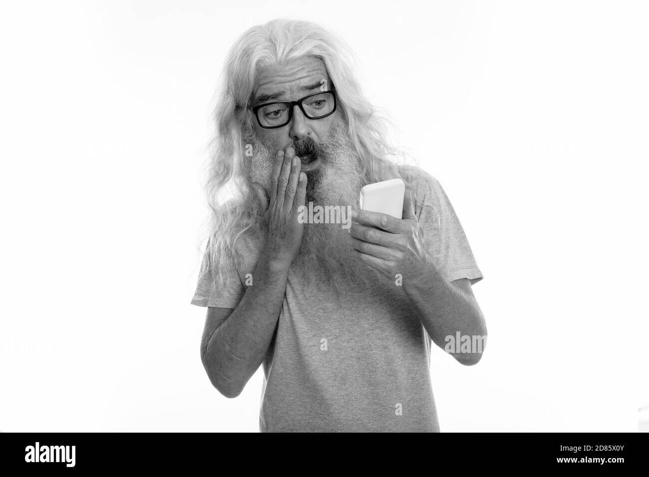 Studio shot der älteren bärtigen Mann mit Handy während geschockt und Mund Stockfoto