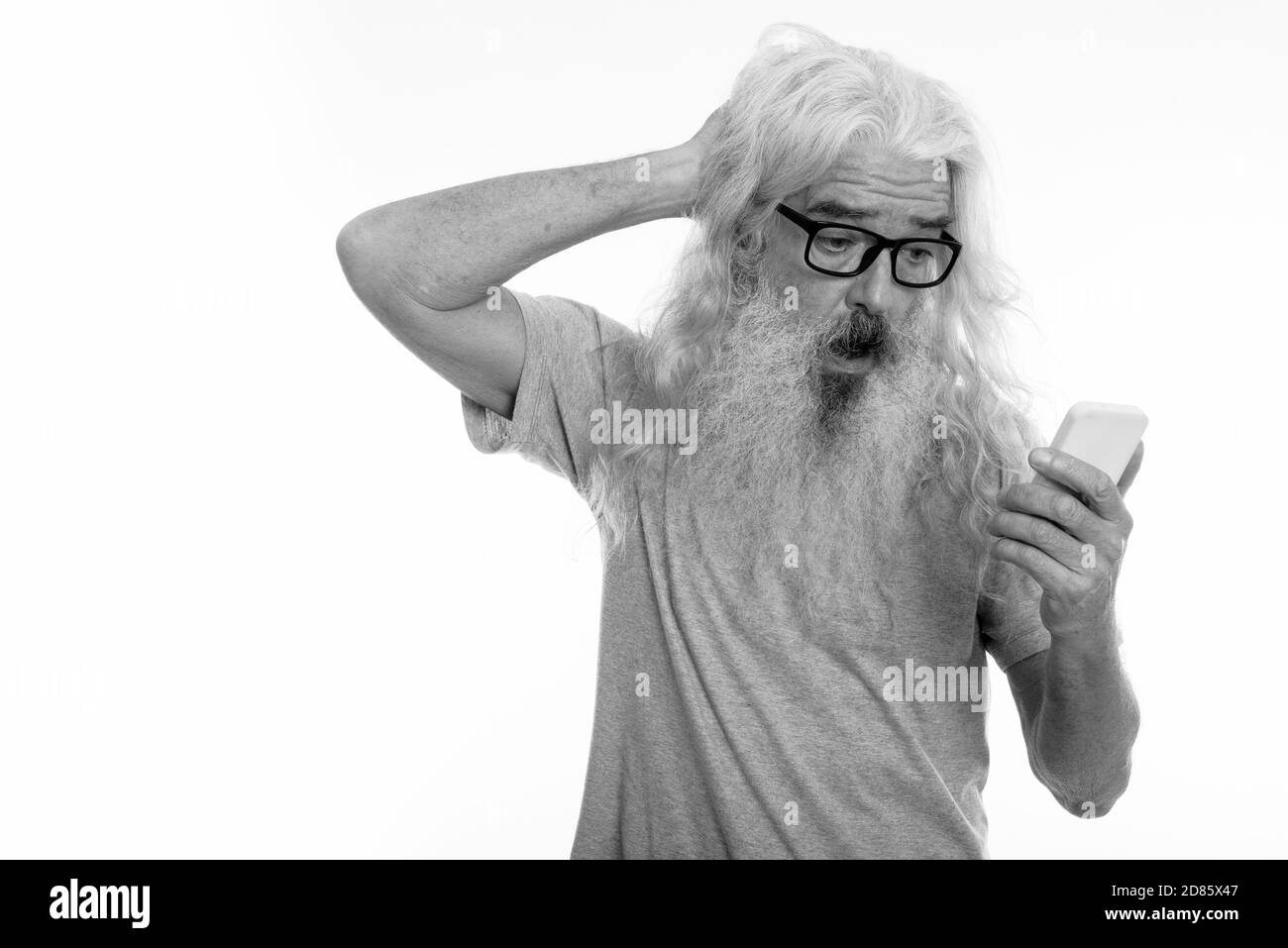 Studio shot der älteren bärtigen Mann verwirrt über Handy während der Suche Stockfoto