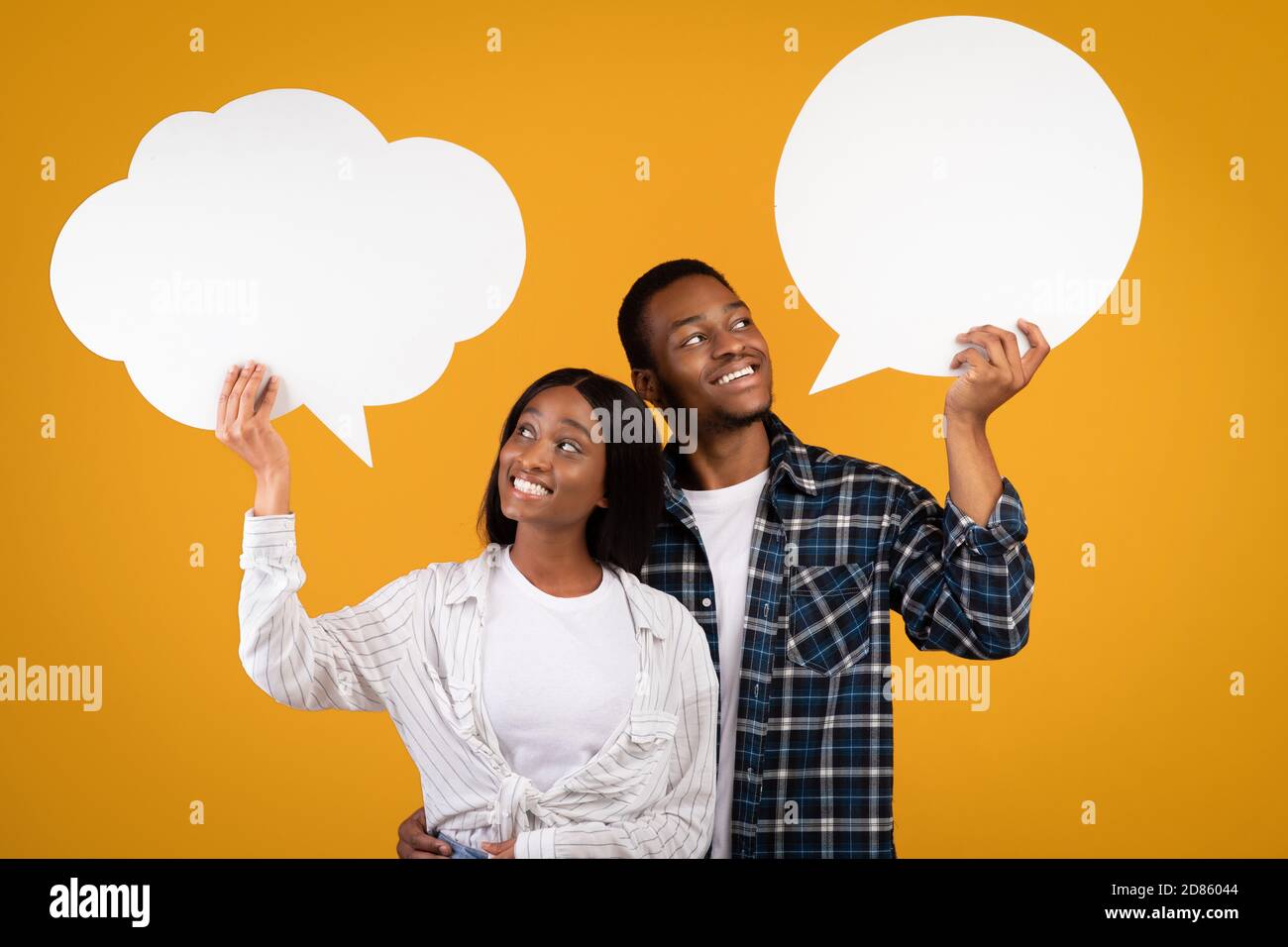 Heerful nachdenklich junge afroamerikanische Kerl und Frau in casual Schauen Sie sich abstrakte Blase für Gedanken Stockfoto