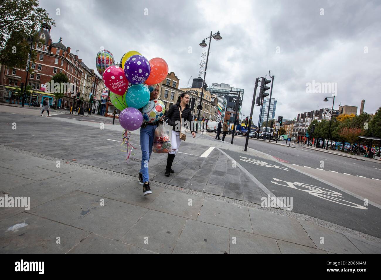 Ein Paar von Frau, die entlang Hoxton High Street mit Geburtstagsparty Ballons, Hoxton, East London, Großbritannien Stockfoto