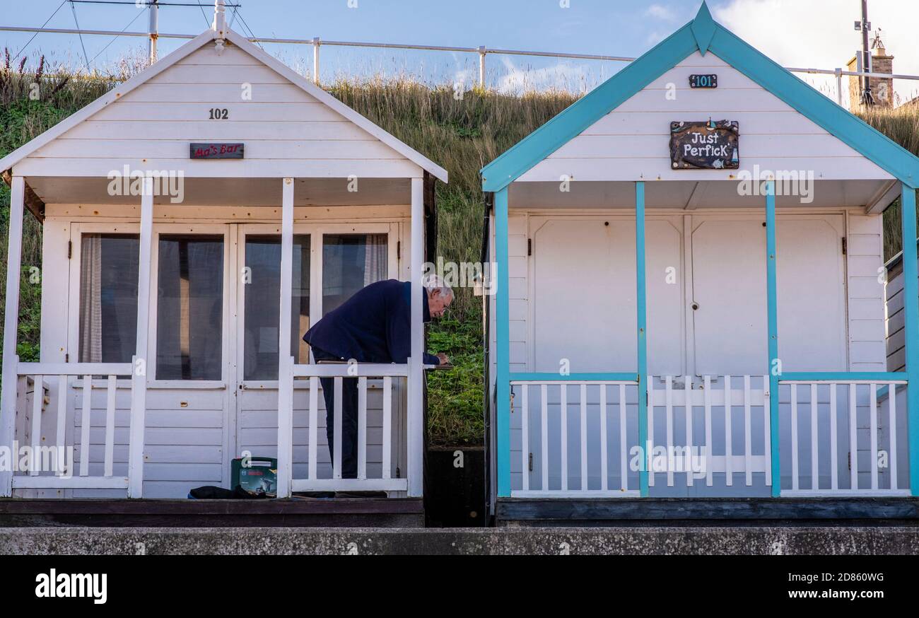 Mann, der sich auf das Geländer der Strandhütte am Meer, Southwold, Suffolk, Großbritannien, stützt Stockfoto