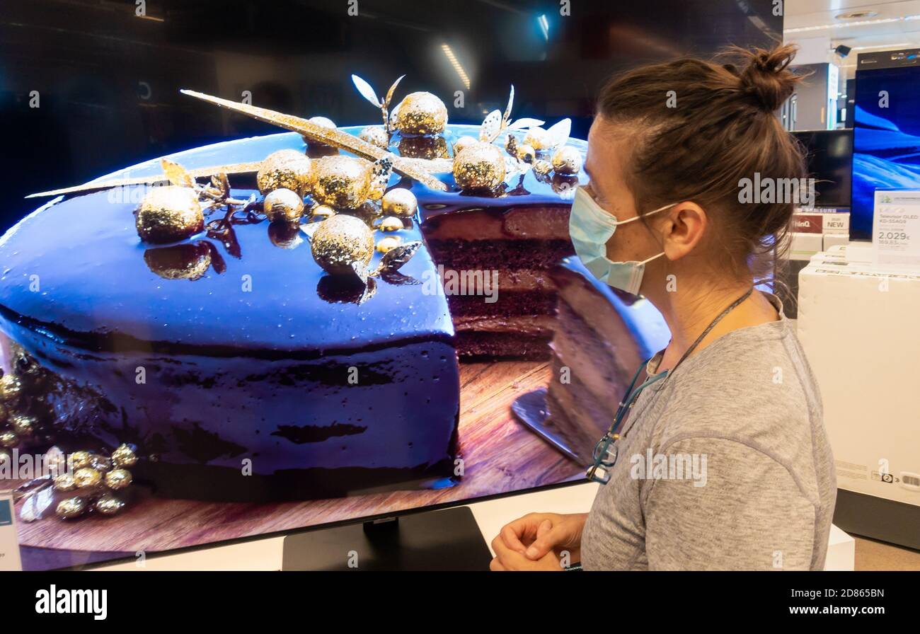 Frau trägt Gesichtsmaske Blick auf Samsung High Definition QLED 8K Q850T Fernseher, TV-Bildschirm im Geschäft. Stockfoto