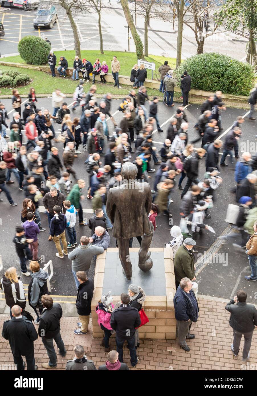 Fans von Newcastle United am Spieltag passieren die Statue des ehemaligen Managers Sir Bobby Robson vor dem St James Park, Newcastle upon Tyne. VEREINIGTES KÖNIGREICH Stockfoto