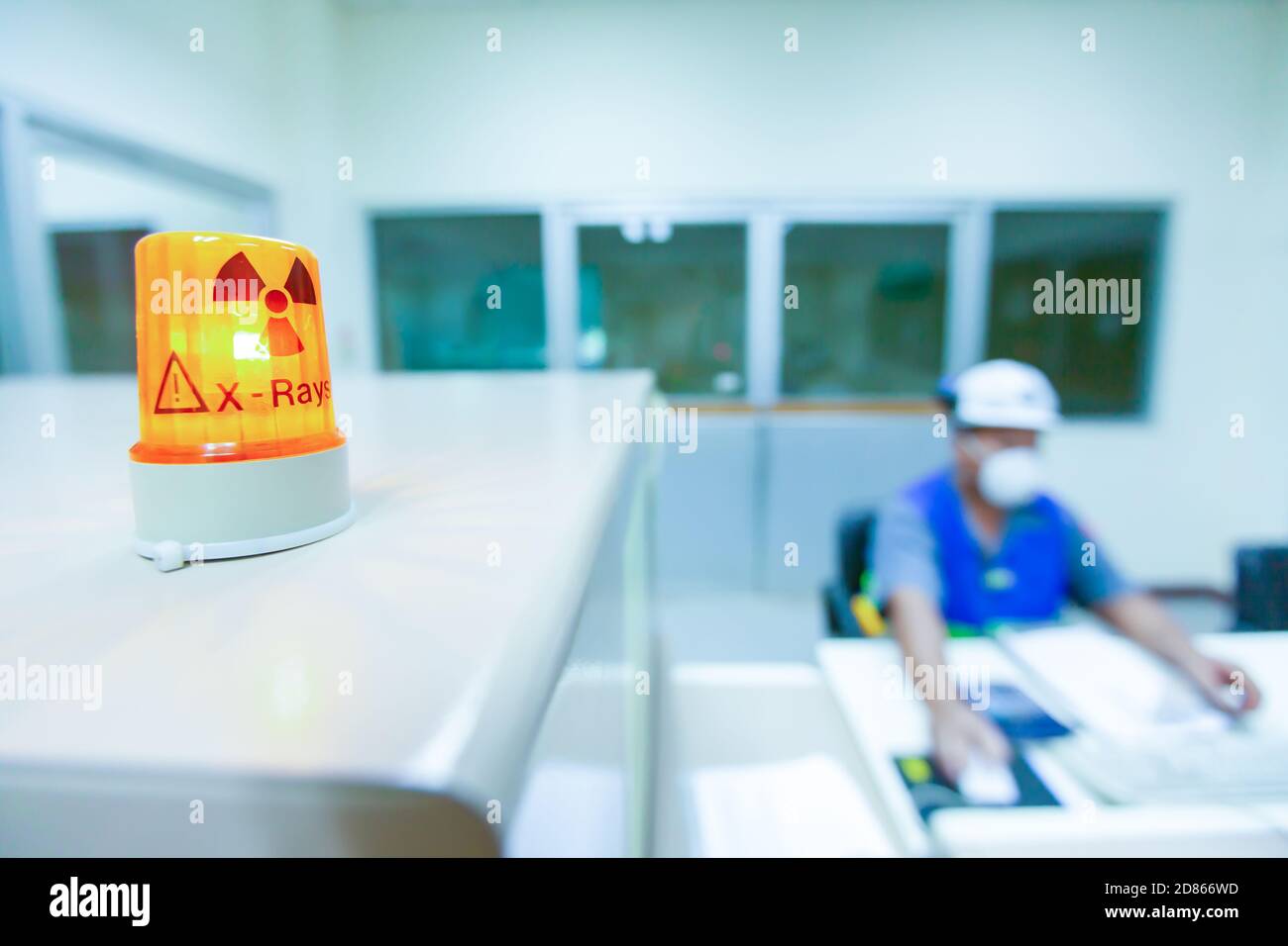 Männlicher wissenschaftlicher Forscher in schützenden Uniformen arbeitet im Röntgenlabor, ionisierende Strahlungsgefahr Symbol im Vordergrund. Selektiver Fokus. Stockfoto